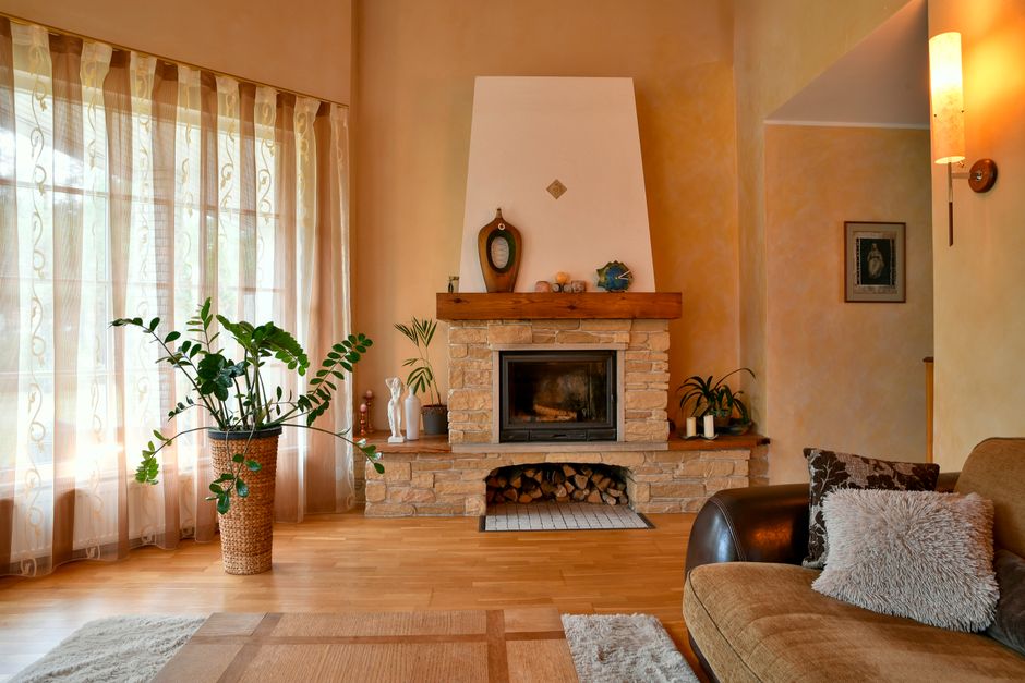 Warm rustic sitting room with stone walls, wooden beams and cosy armchairs